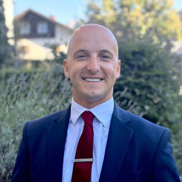 Smiling bald man in a suit and red tie.