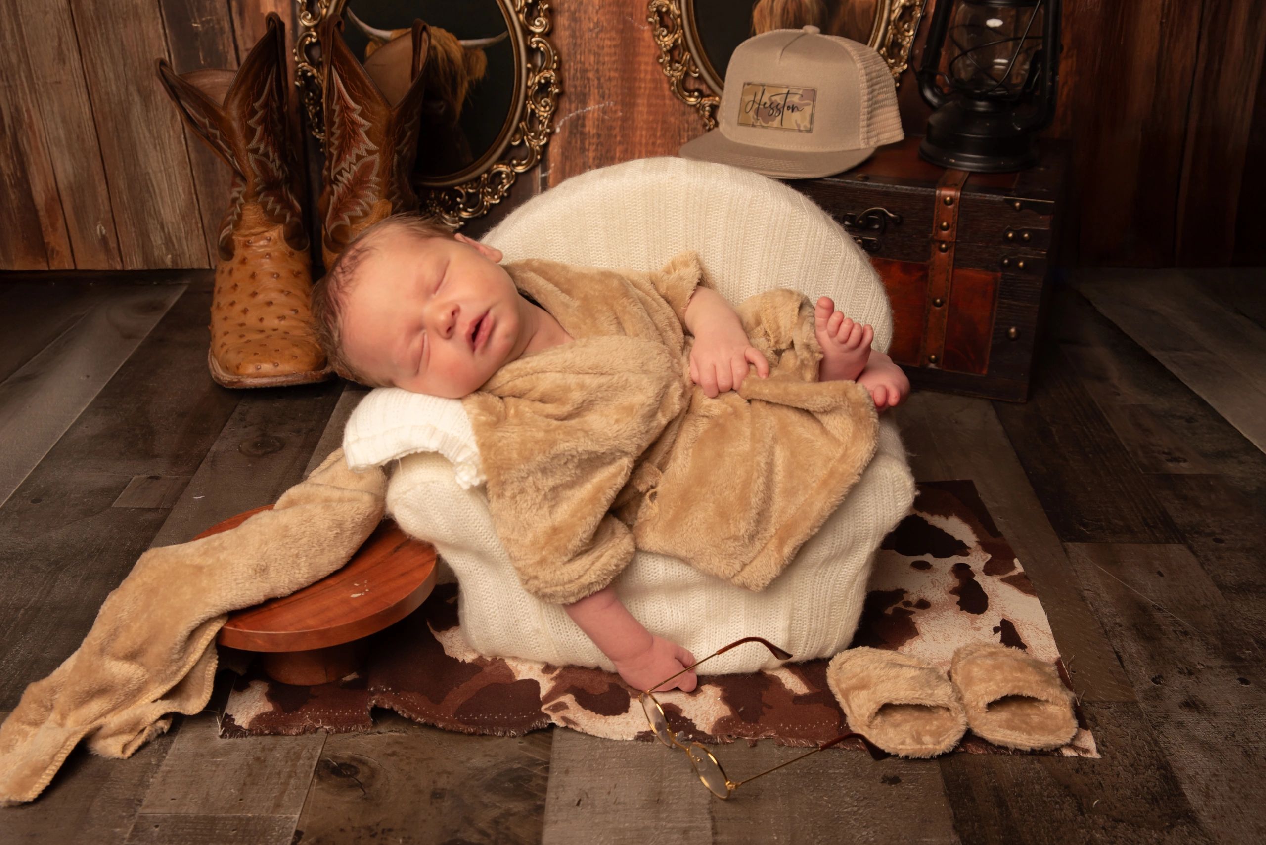 Sleeping baby wrapped in a cozy blanket in a rustic setting.