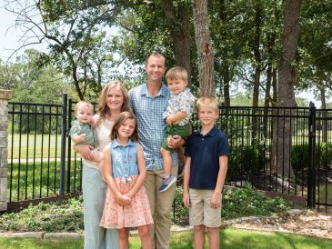 Family portrait with parents and four kids outdoors.