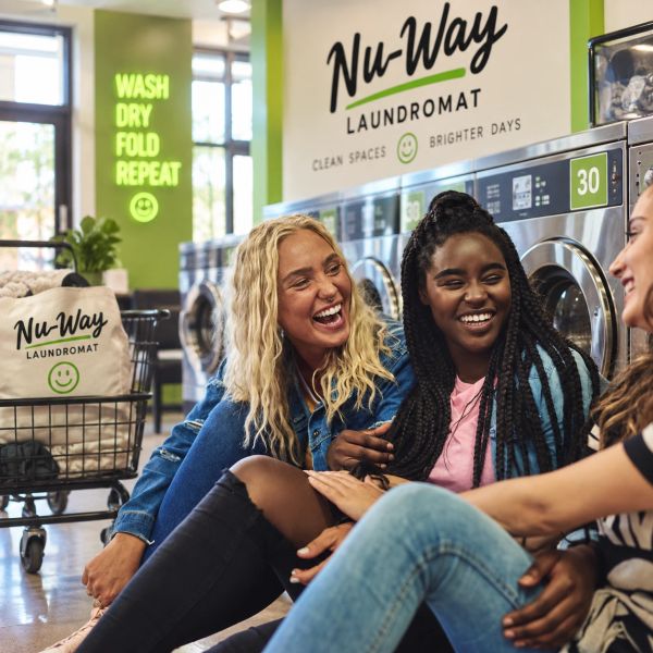Three friends laughing at a laundromat.