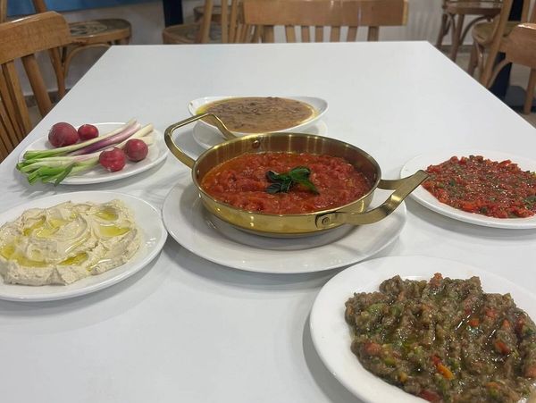 A table with various Middle Eastern dishes and fresh vegetables in a cozy restaurant.
