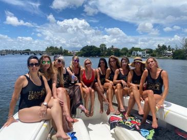 Group of women sitting on a boat by the water.