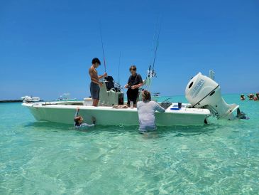 People on and around a boat in clear shallow water.