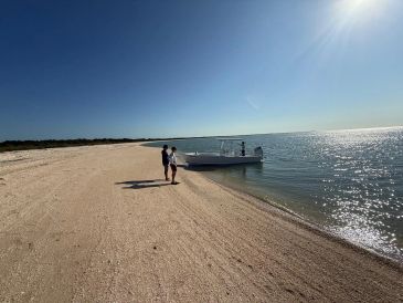 Person near boat on a sunny beach.