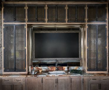 Rustic wooden kitchen cabinets with a built-in sink and faucet under a large framed window.