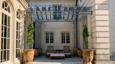 Elegant outdoor seating area with potted plants and a metal pergola.