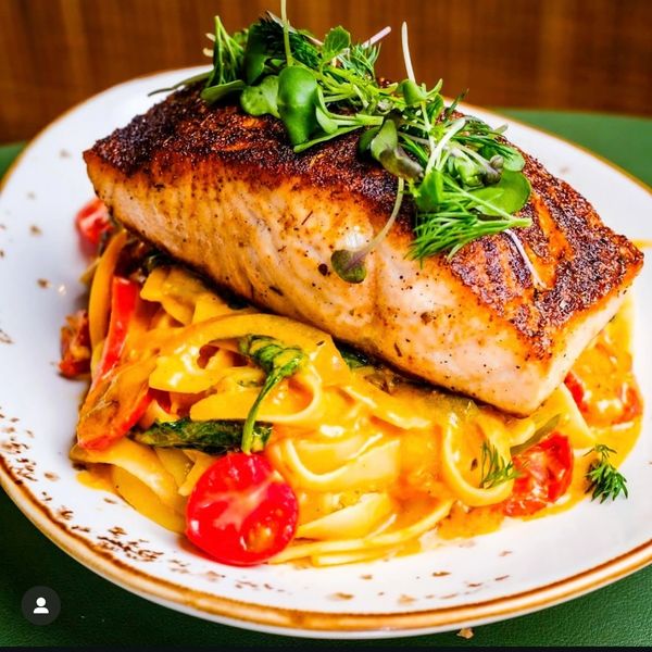 Grilled salmon on creamy pasta with veggies.