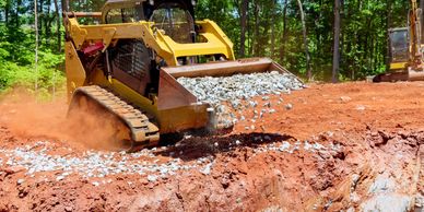 Image of skid steer machine moving dirt on a horse arena construction job