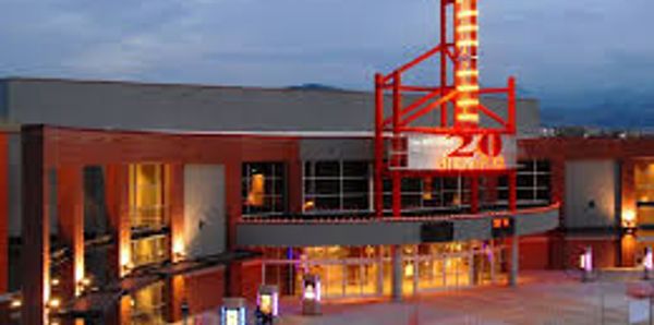 Modern building entrance with red and white illuminated signage at dusk.
