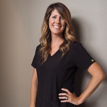 Full view of a lady wearing black dress smiling at the camera