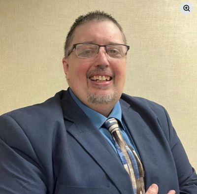 Smiling man in glasses wearing a suit and tie.