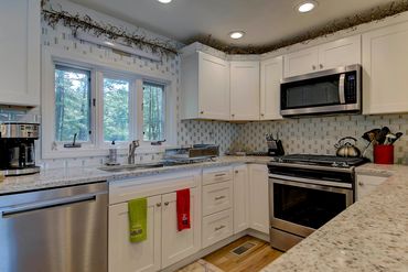 Same redesigned kitchen showing window above the sink and white porcelain and green glass backsplash