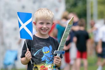 Young Scottish boy, the legacy of our nation's heroes, stands with sword and flag in hand.