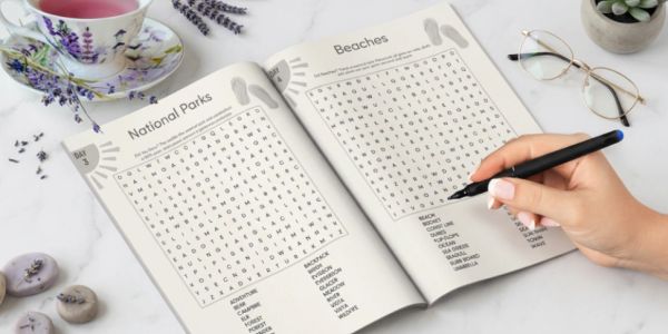 Person solving word search puzzles about national parks and beaches.