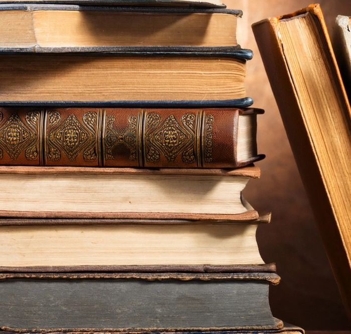 A close-up of stacked vintage books with worn edges and textured covers.