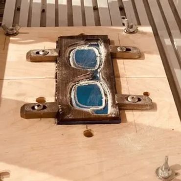 Raw plate laying in the CNC machine after the frame has been cut out.