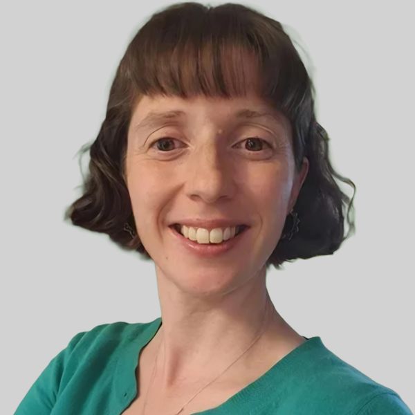 Smiling woman with short curly hair and a teal top.