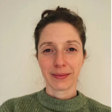 Portrait of a woman with a soft smile wearing a green sweater.