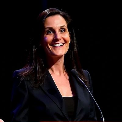 Smiling woman speaking at a podium.