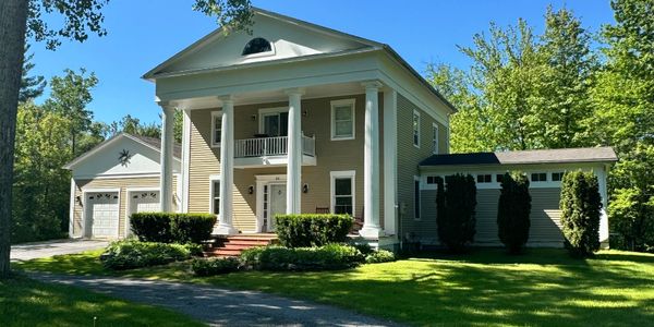A large, classic-style house with tall white columns and a well-kept lawn.
