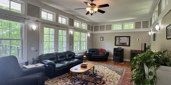 Cozy living room with black leather furniture and natural light from large windows.