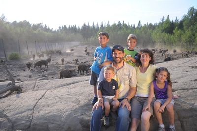 Photo de famille comprenant 2 adultes et 4 enfants posant dans un enclos de sangliers.