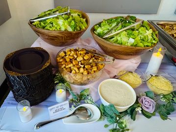 A salad bar setup with fresh greens, croutons, and dressings.