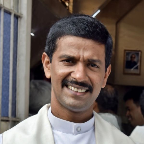 Smiling man with a mustache wearing a white shirt and jacket.
