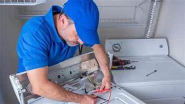 Technician repairing a washing machine in a laundry room.