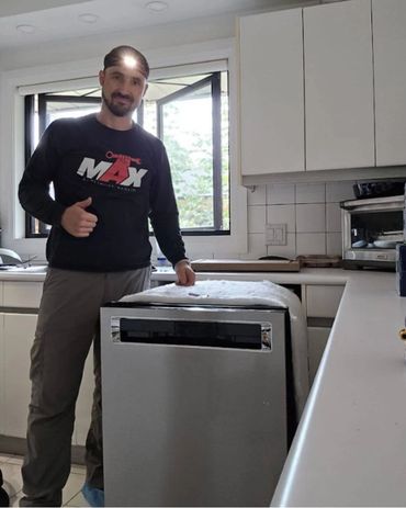 Man giving thumbs up next to a dishwasher in a kitchen.