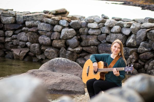 Woman sitting with acoustic guitar on beach photographed by Reichert Photography