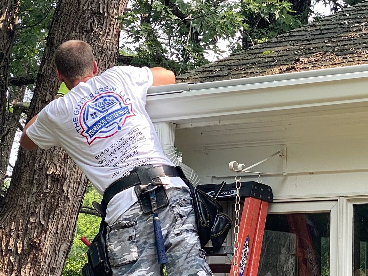 Worker fixing gutters on a house roof.