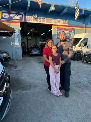 Family standing outside Rodriguez Brothers Auto Service shop during the day.