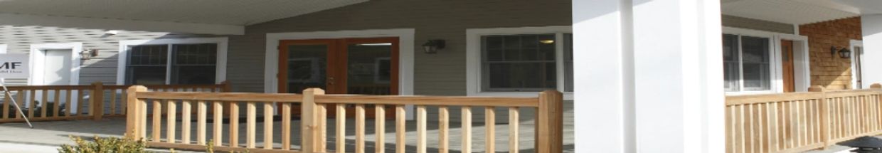 Front porch of a house with wooden railing and double doors.