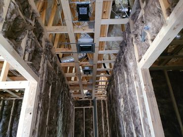 Interior framing with insulation and ductwork in a house under construction.