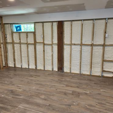 Room under renovation with exposed insulation and new wooden flooring.