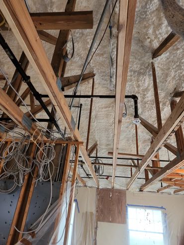 Ceiling with wooden beams, insulation, and electrical wiring in construction.