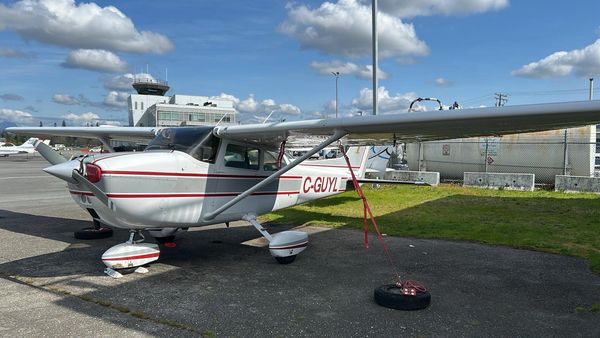 Small white airplane tethered on the ground at an airfield.