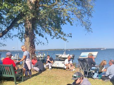 people sitting on the lawn overlooking the water