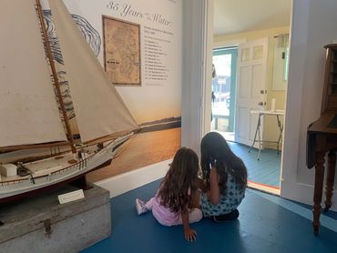 Two girls sitting on the floor in the exhibit