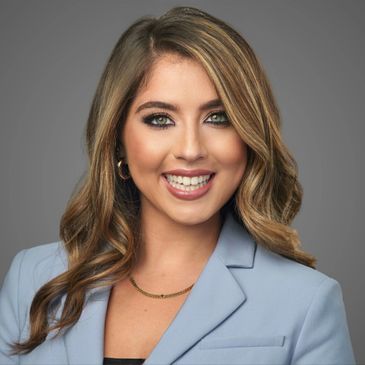 Professional portrait of a smiling woman in a light blue blazer.