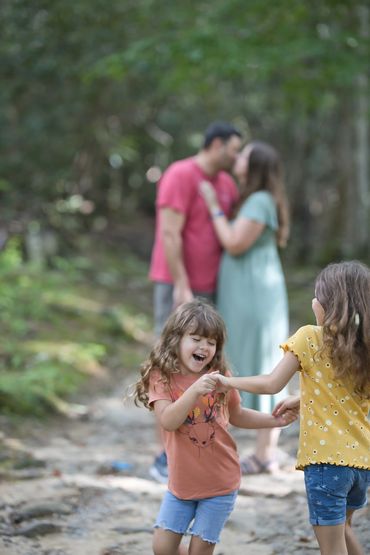 Mom & Dad kissing while daughters dance in the foreground at the Smoky Mountain National Park