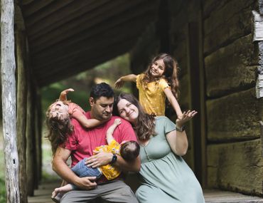 Family of 5 sitting at Bud Ogle Cabin for photos at the Smoky Mountain National Park