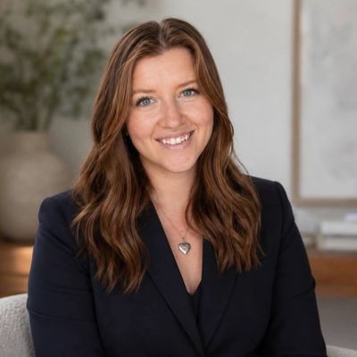 Smiling woman with wavy brown hair in a black blazer.
