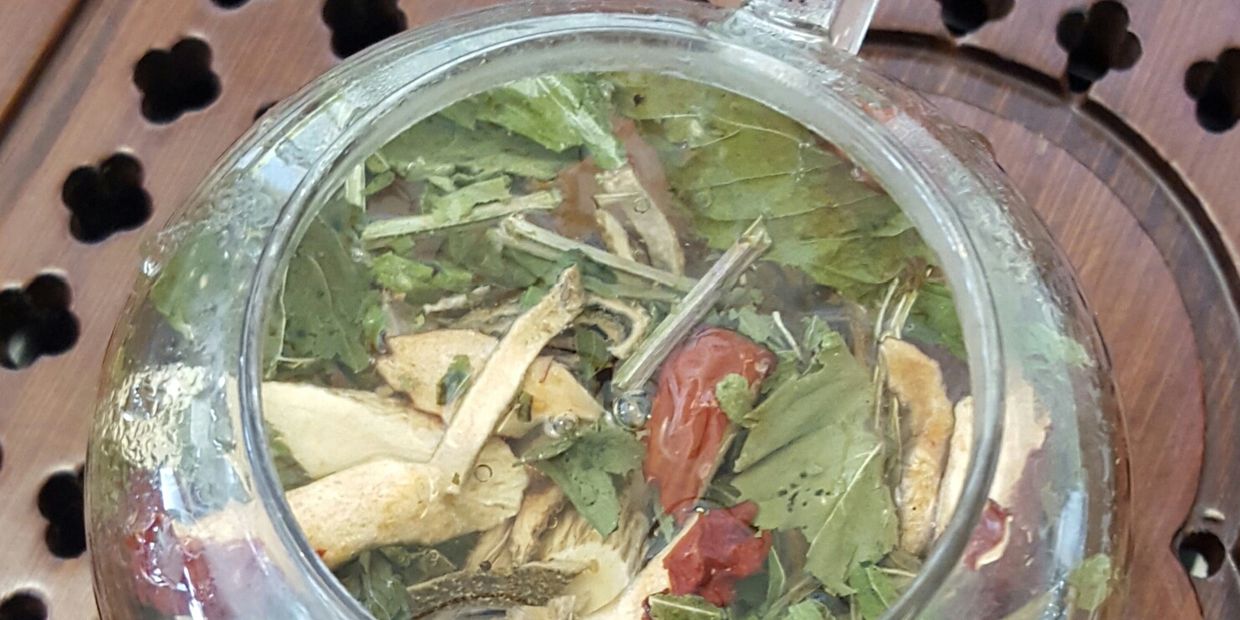 Glass teapot filled with herbs.