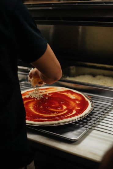 Topping pizza with shredded cheese.