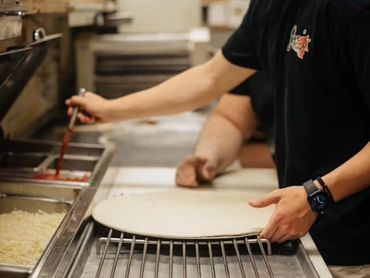 Putting sauce on pizza.