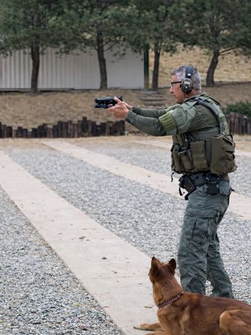 Man with gun and dog at shooting range.