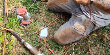 Person working with wires and tools on the ground.