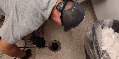 Person unclogging a drain on the floor.